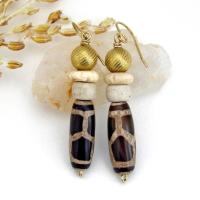 These handmade earrings feature Tibetan agate beads with a brown and tan tribal pattern accented with African beige glass and carved bone beads topped off with gold brass beads. Unique and fun to wear - they'll add a boho tribal flair to your wardrobe. Handmade in the USA by Desert Earth Jewelry.