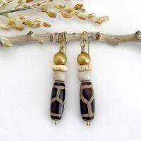 These handmade earrings feature Tibetan agate beads with a brown and tan tribal pattern accented with African beige glass and carved bone beads topped off with gold brass beads. Unique and fun to wear - they'll add a boho tribal flair to your wardrobe. Handmade in the USA by Desert Earth Jewelry.