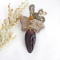 This handcrafted necklace features a carved wood African mask accented with a giraffe print etched agate, golden tiger's eye gemstones and an African carved bone bead. Unique and striking, it'll make a great gift for someone that loves one-of-a-kind ethnic inspired jewelry! It comes on an 18” antiqued brass chain with sturdy hook & eye closure.  Makes a great gift for a man or women that loves African art!
