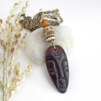 This handcrafted necklace features a carved wood African mask accented with a giraffe print etched agate, golden tiger's eye gemstones and an African carved bone bead. Unique and striking, it'll make a great gift for someone that loves one-of-a-kind ethnic inspired jewelry! It comes on an 18” antiqued brass chain with sturdy hook & eye closure.  Makes a great gift for a man or women that loves African art!