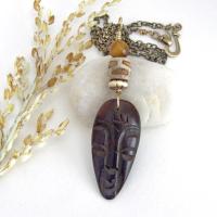 This handcrafted necklace features a carved wood African mask accented with a giraffe print etched agate, golden tiger's eye gemstones and an African carved bone bead. Unique and striking, it'll make a great gift for someone that loves one-of-a-kind ethnic inspired jewelry! It comes on an 18” antiqued brass chain with sturdy hook & eye closure.  Makes a great gift for a man or women that loves African art!