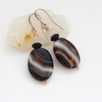 These handcrafted earrings feature natural banded agate gemstones accented with black onyx and white crystal beads. The stones have a unique natural pattern with swirls of orange, black and white. They'll make a great gift for anyone that appreciates the beauty of natural gemstones. Great Halloween and fall colors.