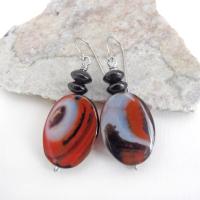 These handcrafted earrings feature natural banded agate gemstones accented with black onyx beads. The stones have a unique natural pattern with swirls of orange, black and white. They'll make a great gift for anyone that appreciates the beauty of natural gemstones. Unique and one of a kind, they'll make a great gift for women that love natural stones.