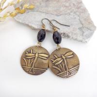 These handmade earrings feature gold brass charms with an embossed nature pattern of dragonflies and leaves. They are accented with black beads and dangle from antiqued brass ear wires. Lightweight and comfortable to wear, they'll make a great gift for a nature lover.