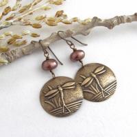 These handmade earrings feature antiqued gold brass charms with an embossed nature pattern of dragonflies and leaves. They are accented with bronze freshwater pearls and dangle from antiqued brass ear wires. Lightweight and comfortable to wear, they'll make a great gift for a nature lover.