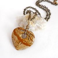This handcrafted pendant necklace has a simplistic earthy charm. It features a natural picture jasper gemstone carved into a heart shape. It's wrapped in antiqued brass wire and comes on an 18" antiqued brass chain. The stone has a natural pattern with markings of tan, mocha brown and black. Makes a great gift to tell someone "I love you" - or a nice addition to your own jewelry collection.