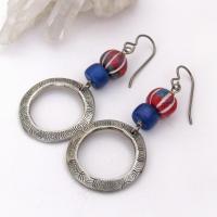 These handcrafted earrings feature silver pewter circle hoops with a hand stamped texture accented with red, white and blue carved clay beads and navy blue glass beads. They have an earthy, boho style and are lightweight and comfortable to wear. 