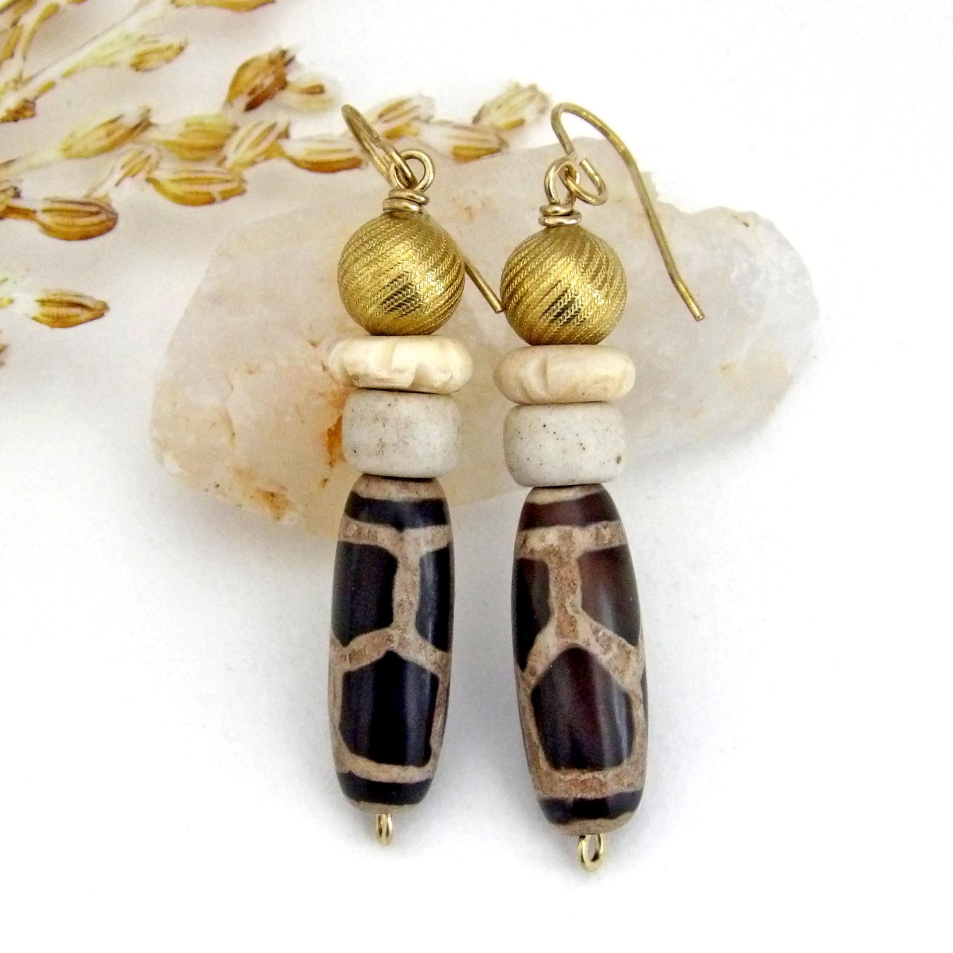 These handmade earrings feature Tibetan agate beads with a brown and tan tribal pattern accented with African beige glass and carved bone beads topped off with gold brass beads. Unique and fun to wear - they'll add a boho tribal flair to your wardrobe. Handmade in the USA by Desert Earth Jewelry.