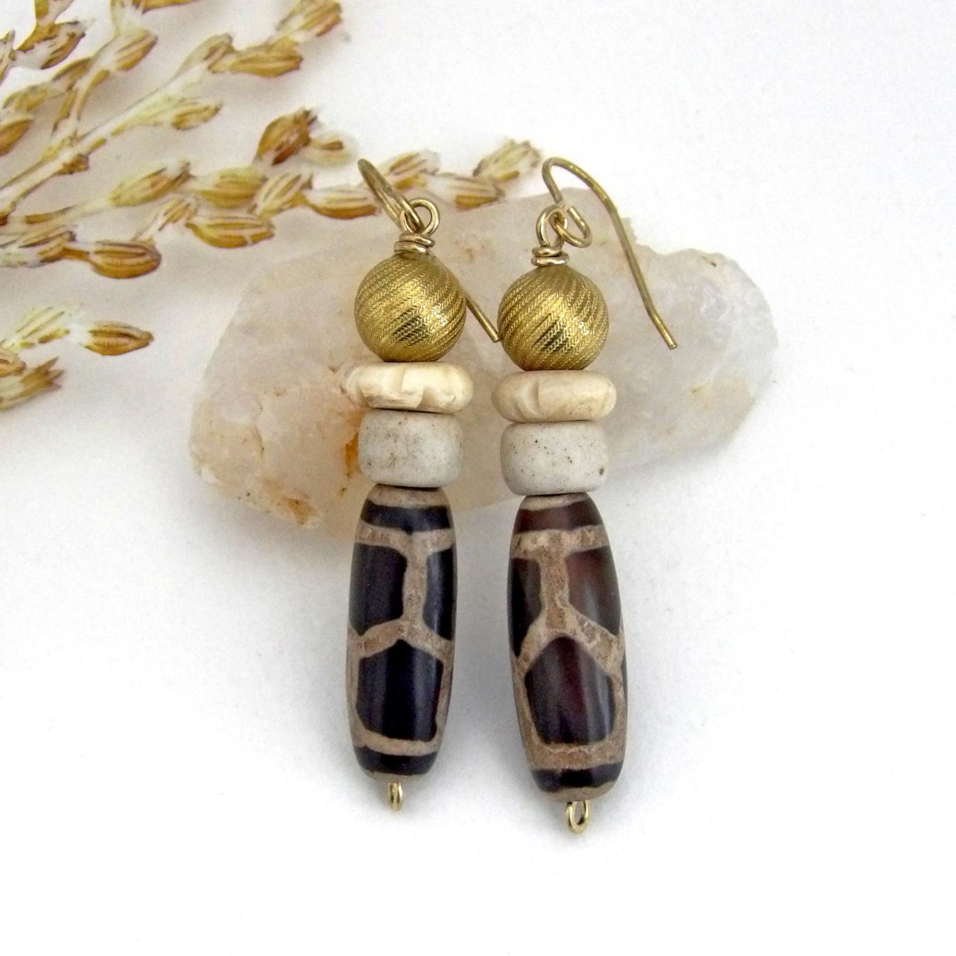 These handmade earrings feature Tibetan agate beads with a brown and tan tribal pattern accented with African beige glass and carved bone beads topped off with gold brass beads. Unique and fun to wear - they'll add a boho tribal flair to your wardrobe. Handmade in the USA by Desert Earth Jewelry.