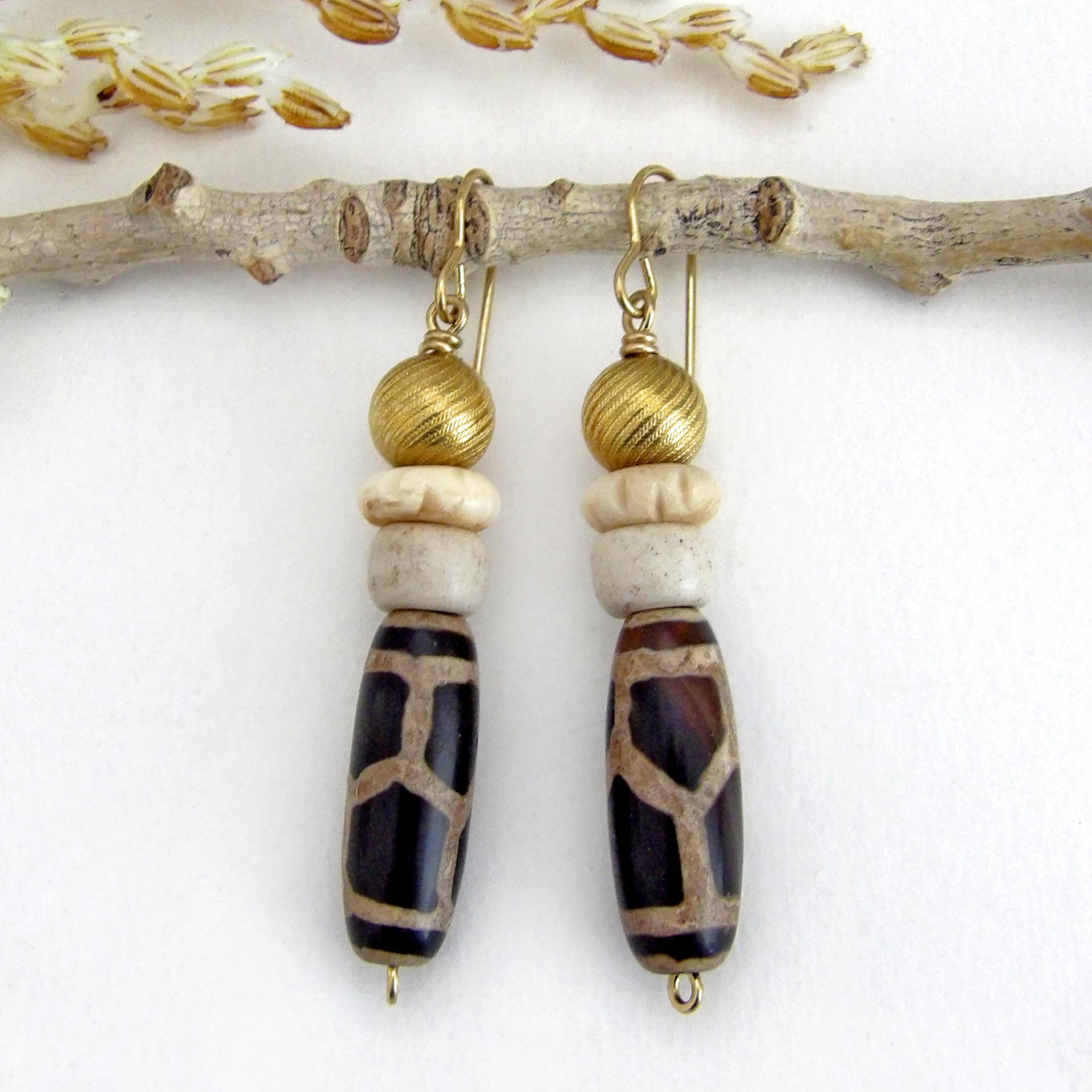 These handmade earrings feature Tibetan agate beads with a brown and tan tribal pattern accented with African beige glass and carved bone beads topped off with gold brass beads. Unique and fun to wear - they'll add a boho tribal flair to your wardrobe. Handmade in the USA by Desert Earth Jewelry.