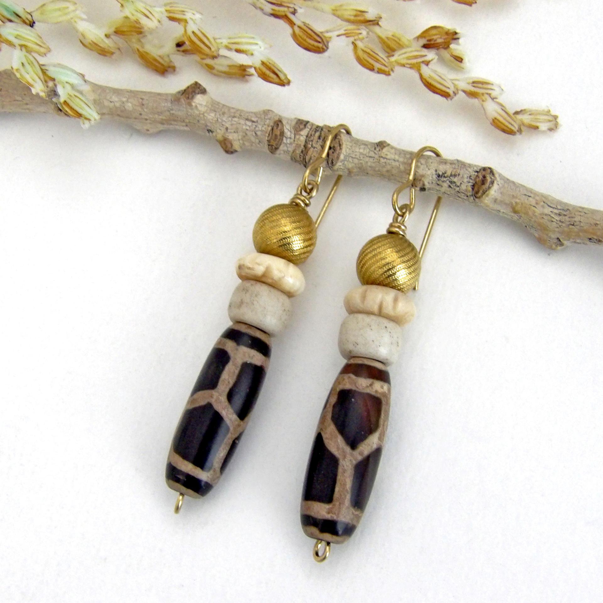 These handmade earrings feature Tibetan agate beads with a brown and tan tribal pattern accented with African beige glass and carved bone beads topped off with gold brass beads. Unique and fun to wear - they'll add a boho tribal flair to your wardrobe. Handmade in the USA by Desert Earth Jewelry.