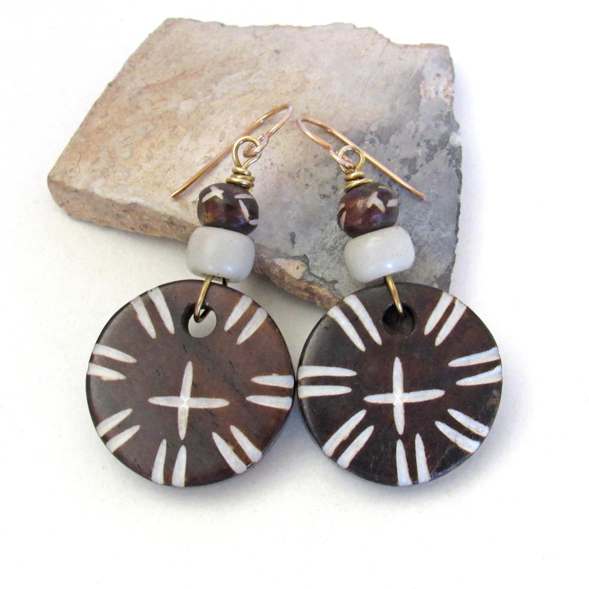 These handmade earrings feature large round African batik bone beads with a carved tribal pattern accented with smaller African carved bone beads and African glass beads. They have an exotic, ethnic tribal style and are sure to make a bold striking statement.
