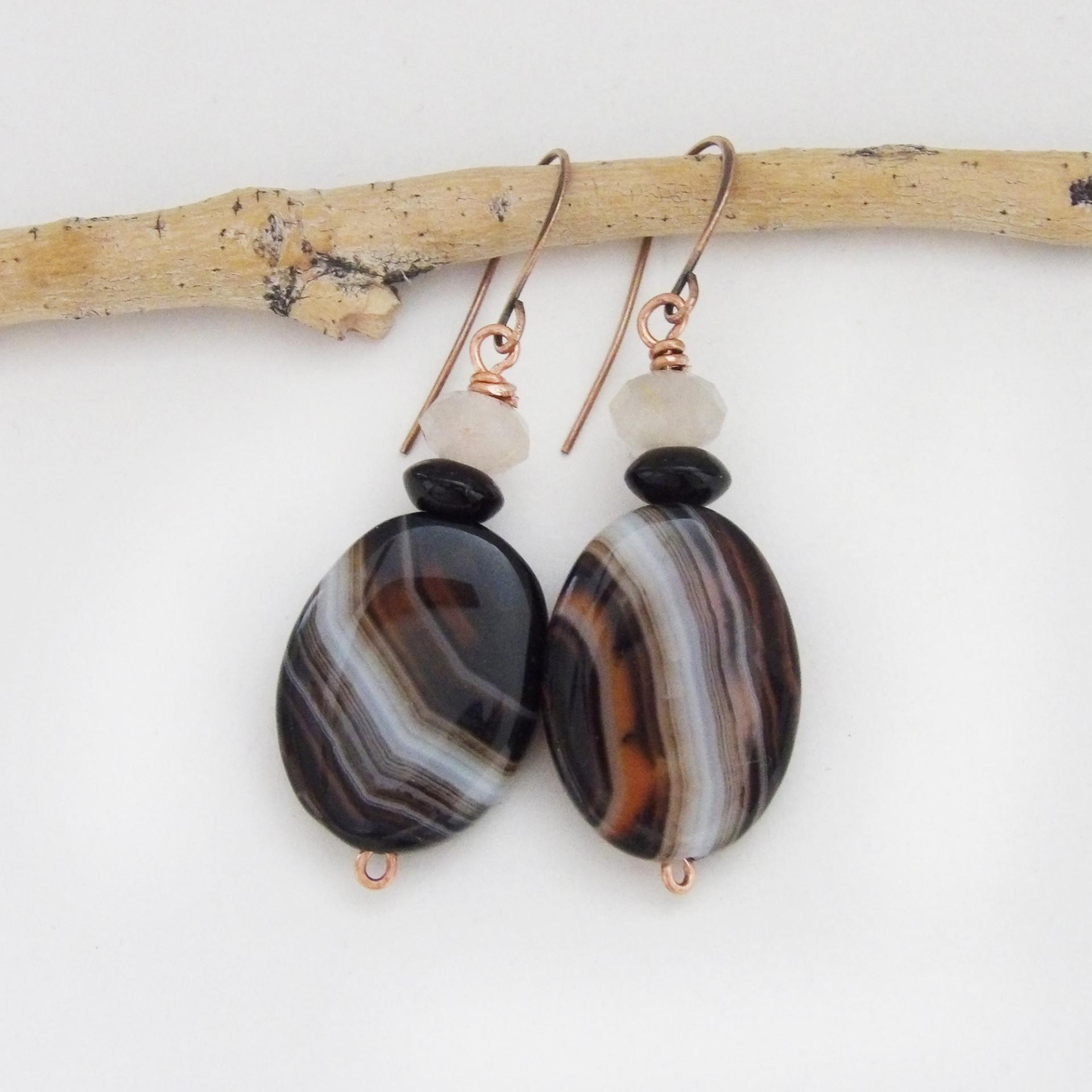 These handcrafted earrings feature natural banded agate gemstones accented with black onyx and white crystal beads. The stones have a unique natural pattern with swirls of orange, black and white. They'll make a great gift for anyone that appreciates the beauty of natural gemstones. Great Halloween and fall colors. Unique and one-of-a-kind, they'll make a great gift for a natural gemstone lover.