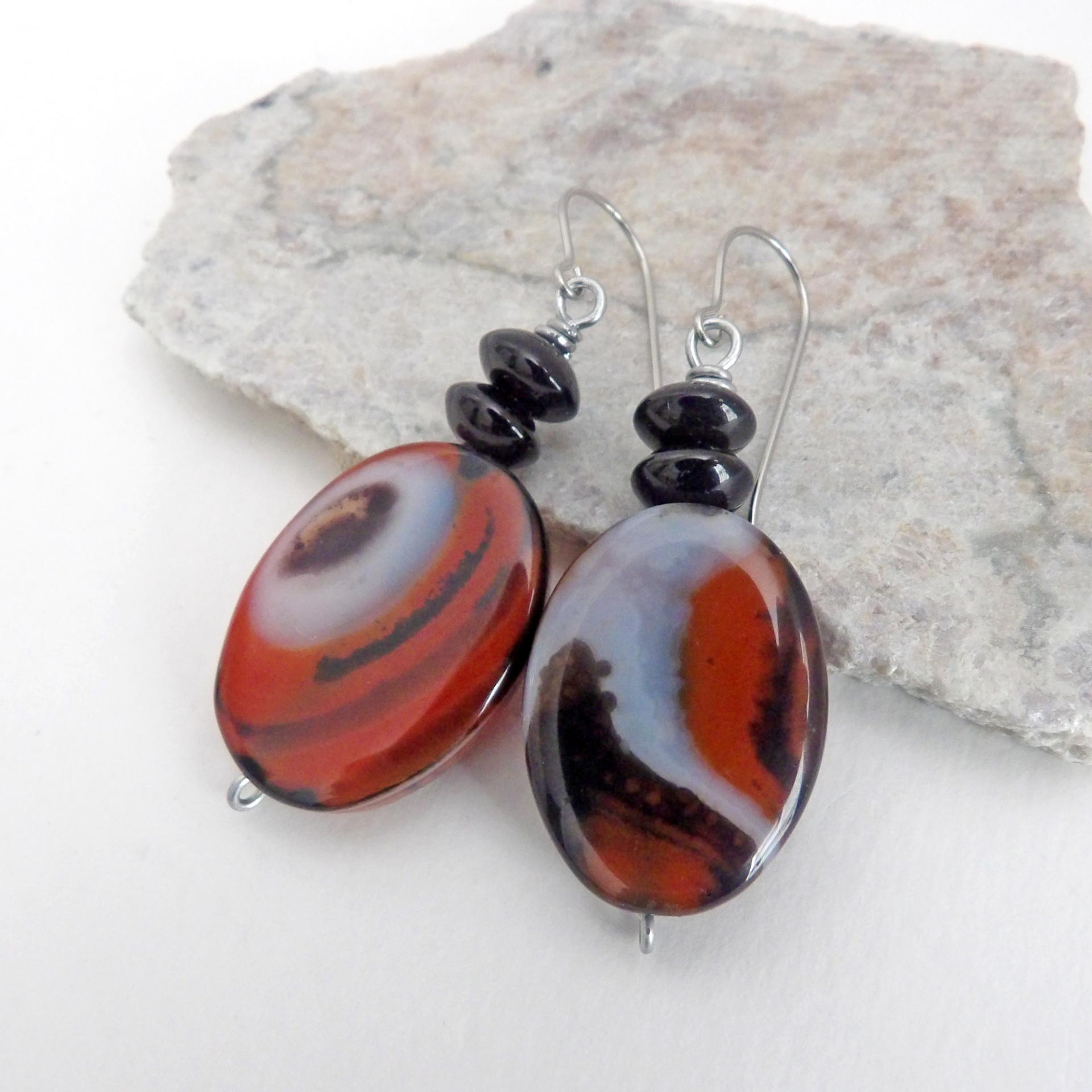 These handcrafted earrings feature natural banded agate gemstones accented with black onyx beads. The stones have a unique natural pattern with swirls of orange, black and white. They'll make a great gift for anyone that appreciates the beauty of natural gemstones. Unique and one of a kind, they'll make a great gift for women that love natural stones.