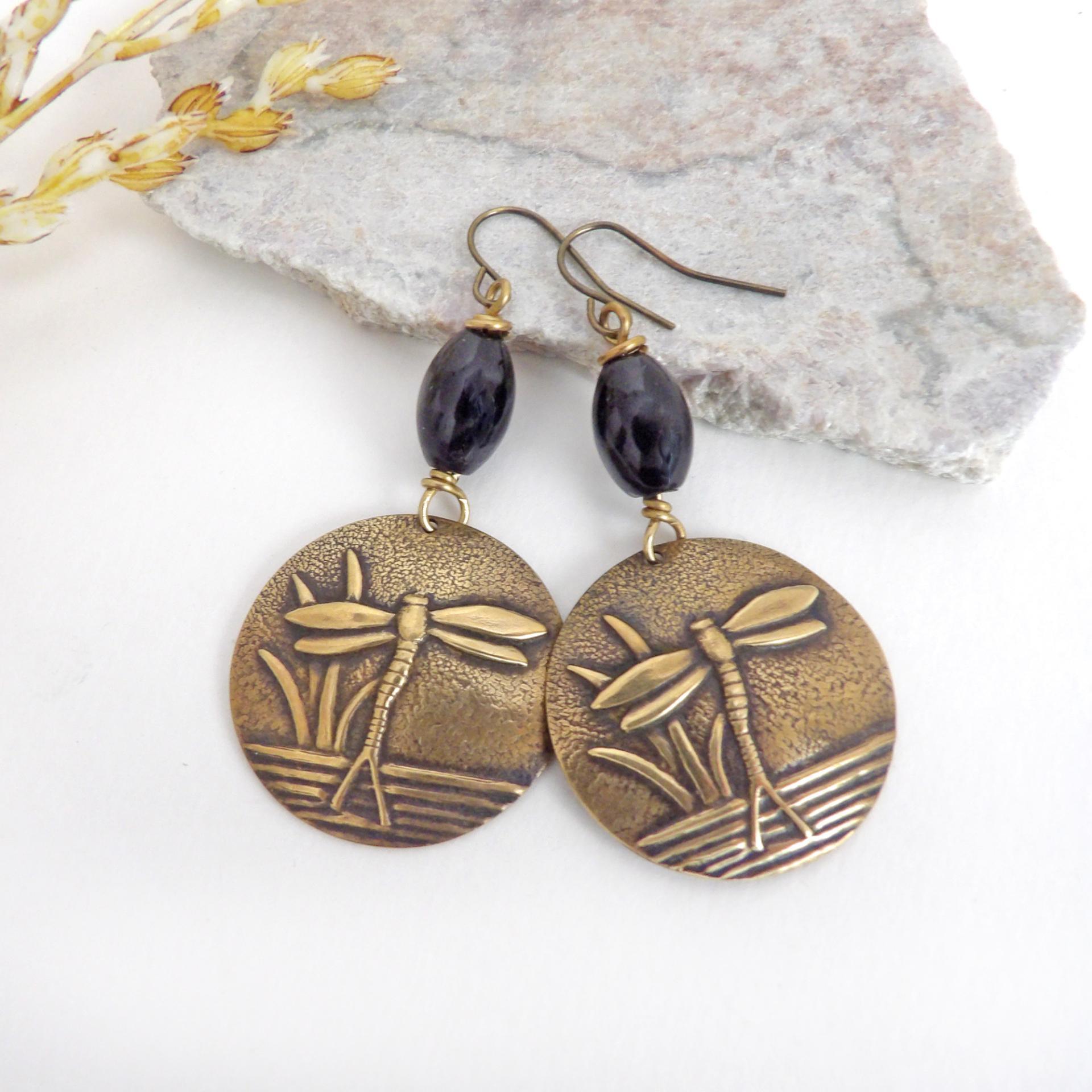 These handmade earrings feature gold brass charms with an embossed nature pattern of dragonflies and leaves. They are accented with black beads and dangle from antiqued brass ear wires. Lightweight and comfortable to wear, they'll make a great gift for a nature lover.