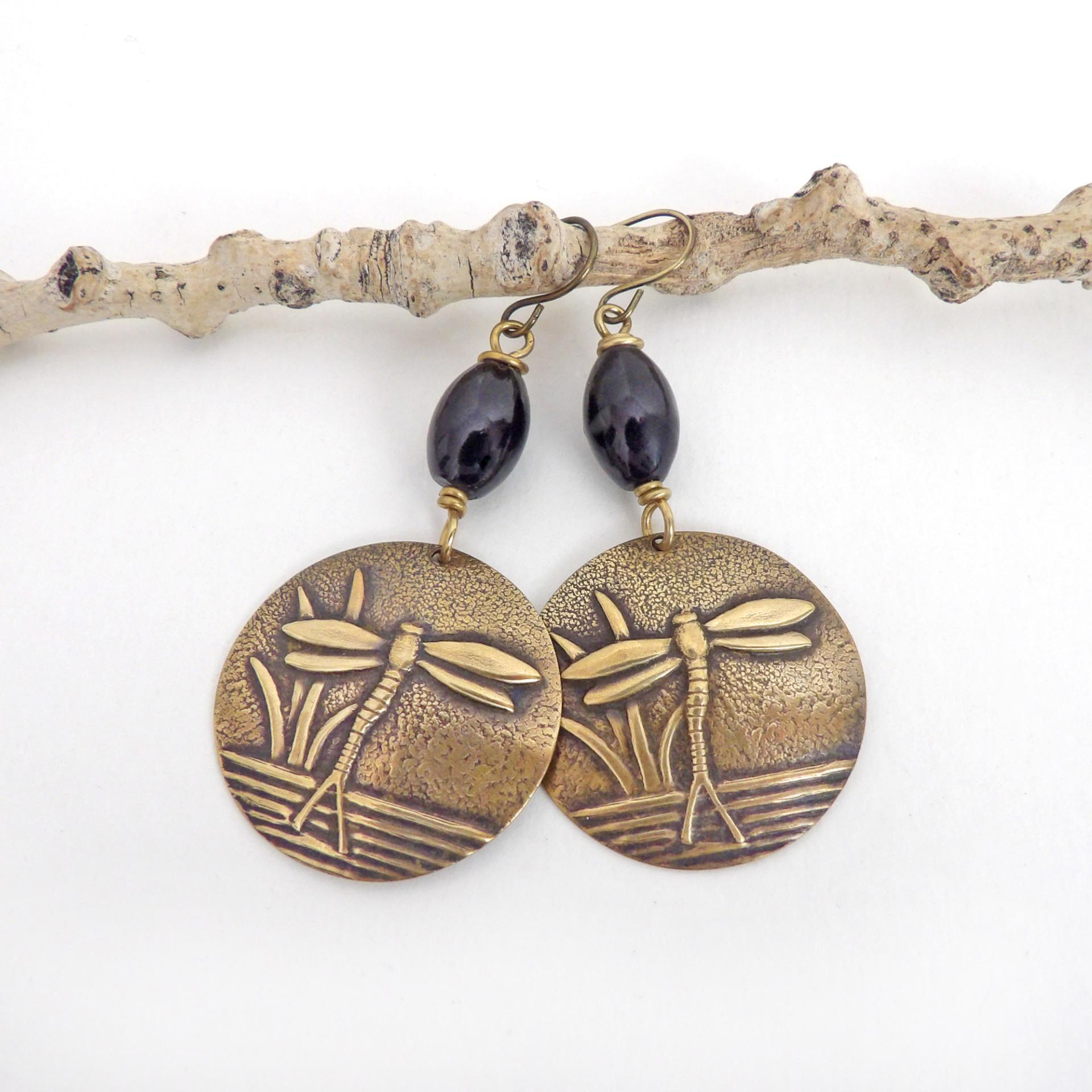These handmade earrings feature gold brass charms with an embossed nature pattern of dragonflies and leaves. They are accented with black beads and dangle from antiqued brass ear wires. Lightweight and comfortable to wear, they'll make a great gift for a nature lover.