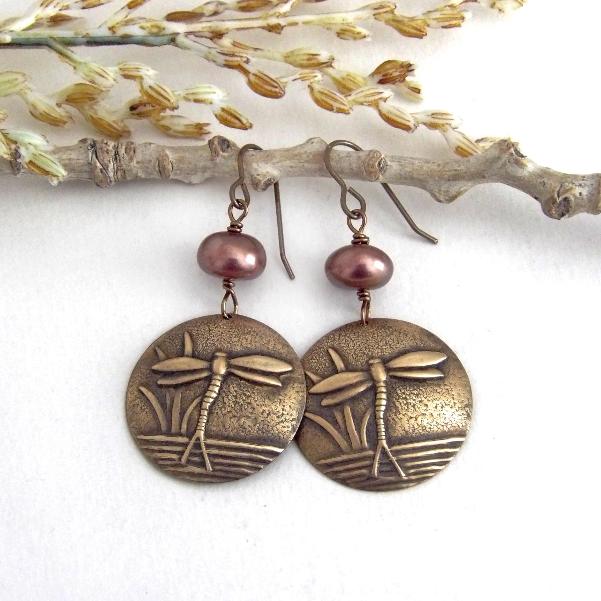 These handmade earrings feature antiqued gold brass charms with an embossed nature pattern of dragonflies and leaves. They are accented with bronze freshwater pearls and dangle from antiqued brass ear wires. Lightweight and comfortable to wear, they'll make a great gift for a nature lover.