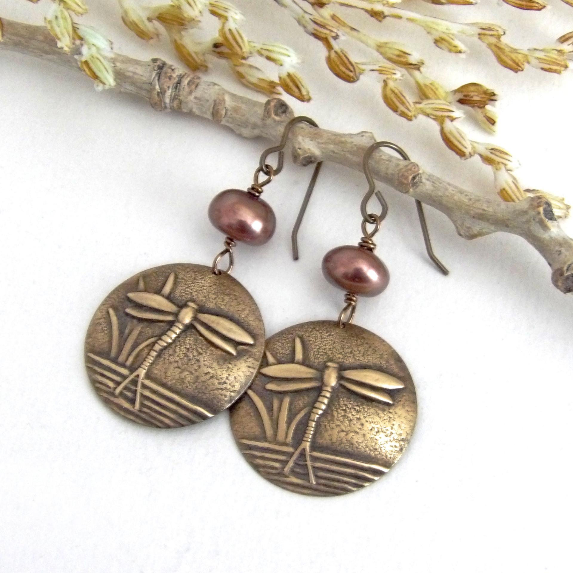 These handmade earrings feature antiqued gold brass charms with an embossed nature pattern of dragonflies and leaves. They are accented with bronze freshwater pearls and dangle from antiqued brass ear wires. Lightweight and comfortable to wear, they'll make a great gift for a nature lover.