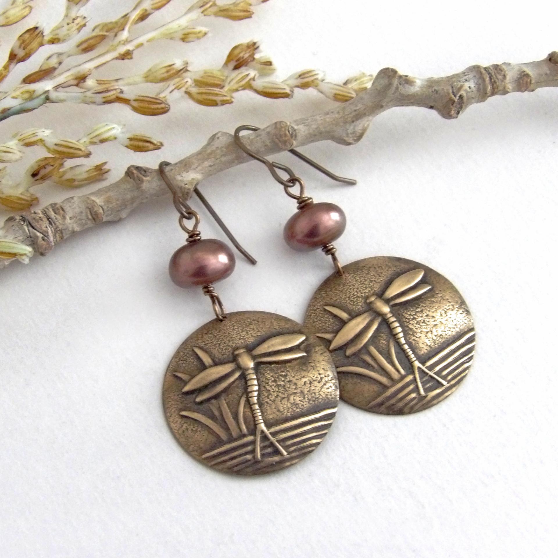 These handmade earrings feature antiqued gold brass charms with an embossed nature pattern of dragonflies and leaves. They are accented with bronze freshwater pearls and dangle from antiqued brass ear wires. Lightweight and comfortable to wear, they'll make a great gift for a nature lover.