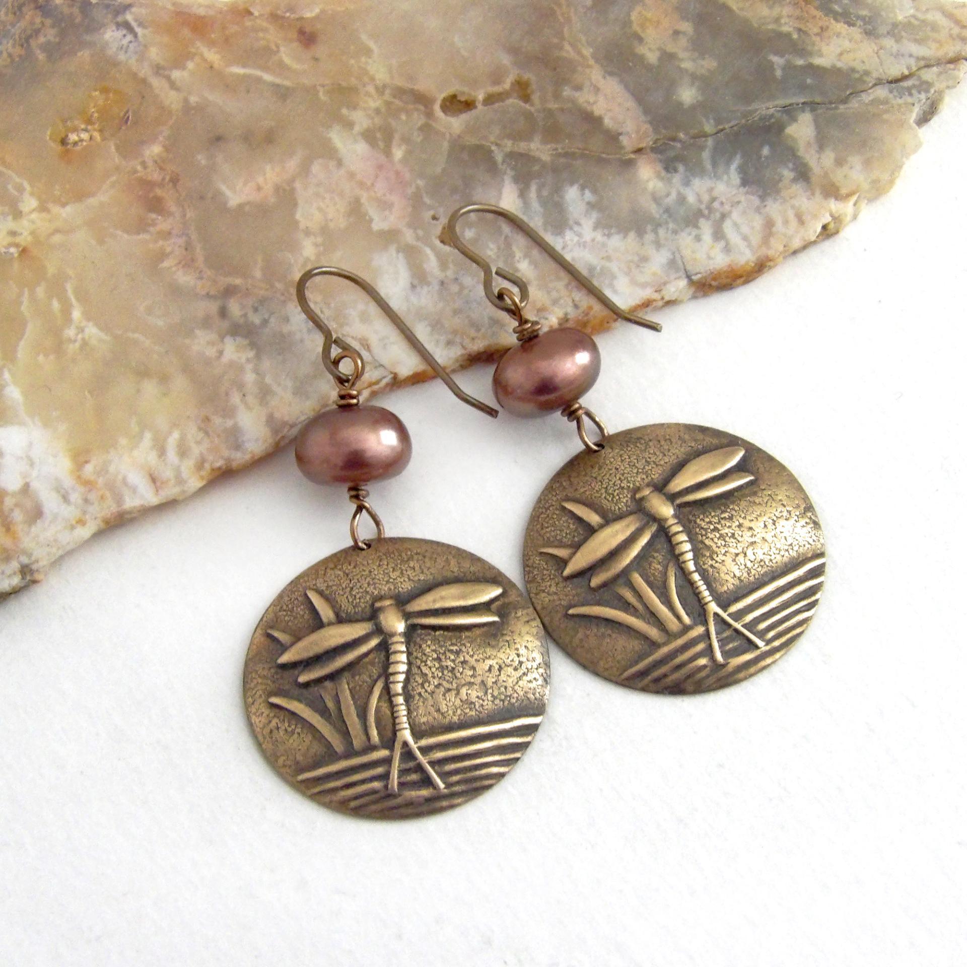 These handmade earrings feature antiqued gold brass charms with an embossed nature pattern of dragonflies and leaves. They are accented with bronze freshwater pearls and dangle from antiqued brass ear wires. Lightweight and comfortable to wear, they'll make a great gift for a nature lover.