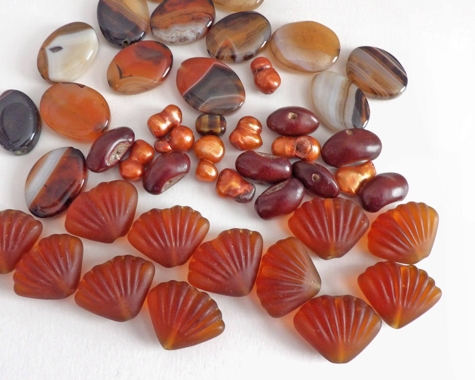 Mixed bead lot for jewelry making / beading / craft supply.  Lot consists of 14 pieces of oval-shaped banded agate beads (black orange white tones with various matrix patterns). Measures approximately 7/8" to 1" in length and 3/4" in width - drilled top to bottom. 12 pieces of burnt orange seashell shaped beads. Measures approximately 1" at widest point and 3/4" in length - drilled top to bottom 9 bright orange organically shaped freshwater pearl beads - drilled 8 dark reddish-brown dried bean beads