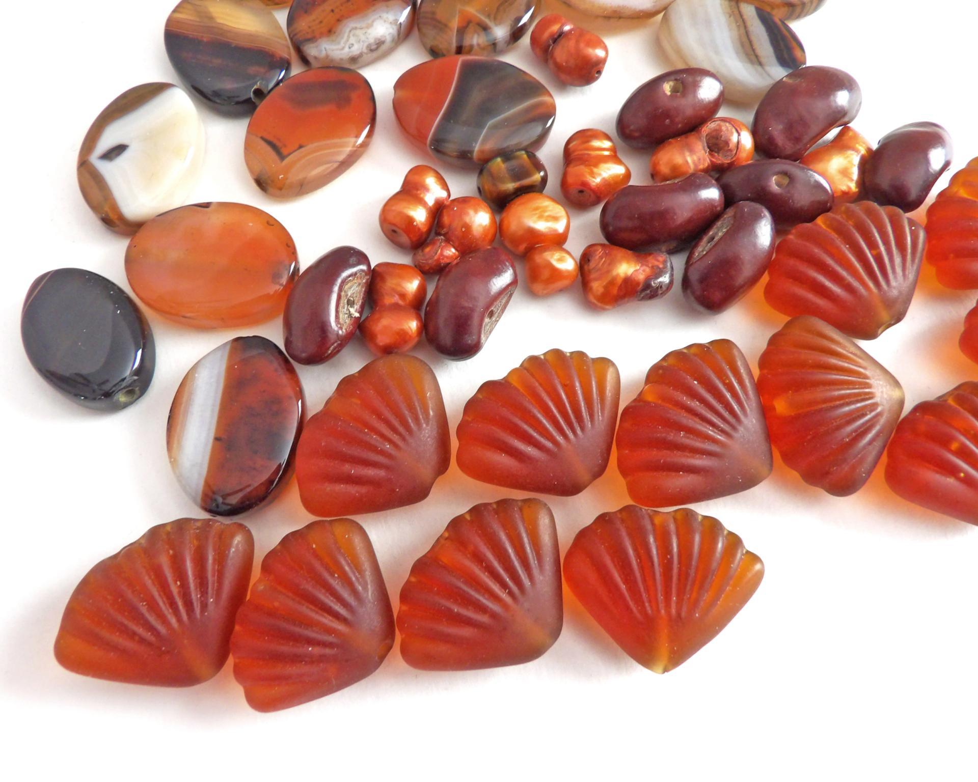 Mixed bead lot for jewelry making / beading / craft supply.  Lot consists of 14 pieces of oval-shaped banded agate beads (black orange white tones with various matrix patterns). Measures approximately 7/8" to 1" in length and 3/4" in width - drilled top to bottom. 12 pieces of burnt orange seashell shaped beads. Measures approximately 1" at widest point and 3/4" in length - drilled top to bottom 9 bright orange organically shaped freshwater pearl beads - drilled 8 dark reddish-brown dried bean beads