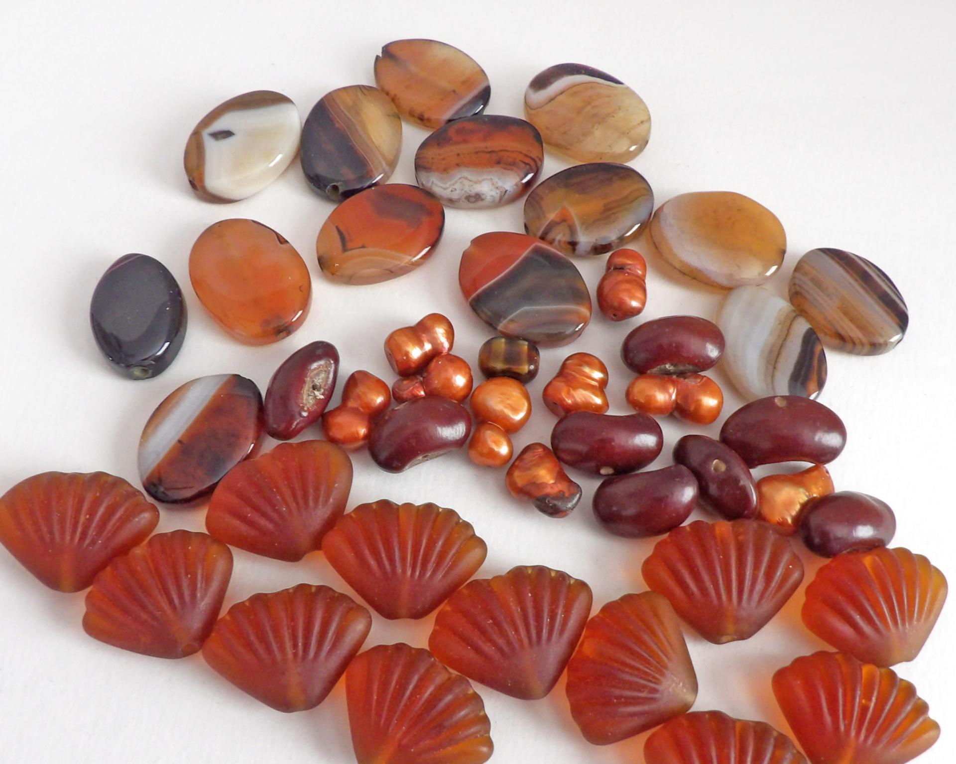 Mixed bead lot for jewelry making / beading / craft supply.  Lot consists of 14 pieces of oval-shaped banded agate beads (black orange white tones with various matrix patterns). Measures approximately 7/8" to 1" in length and 3/4" in width - drilled top to bottom. 12 pieces of burnt orange seashell shaped beads. Measures approximately 1" at widest point and 3/4" in length - drilled top to bottom 9 bright orange organically shaped freshwater pearl beads - drilled 8 dark reddish-brown dried bean beads