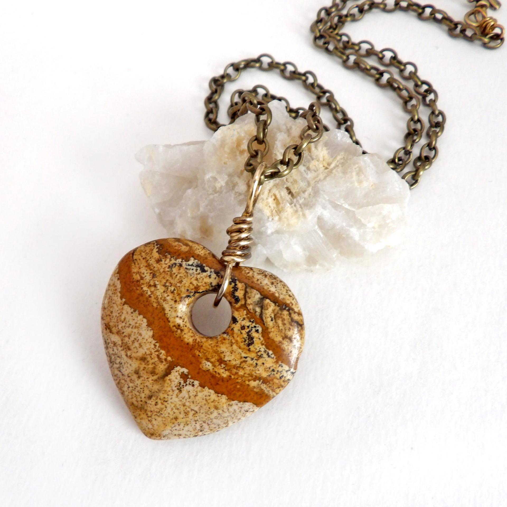 This handcrafted pendant necklace has a simplistic earthy charm. It features a natural picture jasper gemstone carved into a heart shape. It's wrapped in antiqued brass wire and comes on an 18" antiqued brass chain. The stone has a natural pattern with markings of tan, mocha brown and black. Makes a great gift to tell someone "I love you" - or a nice addition to your own jewelry collection.