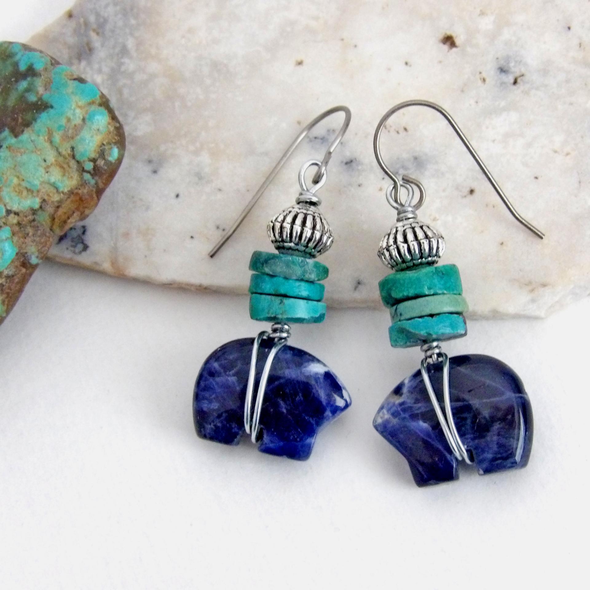 Small and cute, these zuni bear earrings feature natural blue sodalite gemstones carved into zuni bear shapes wrapped in steel wire and accented with turquoise heishi and silver tone pewter beads. They'll make a great gift for an animal / bear lover or anyone that loves southwestern style! These carved stone animals are believed by the Zuni people to hold the living spirit and power of the bear which represents healing, protection, introspection, and is the revered Guardian of the West.