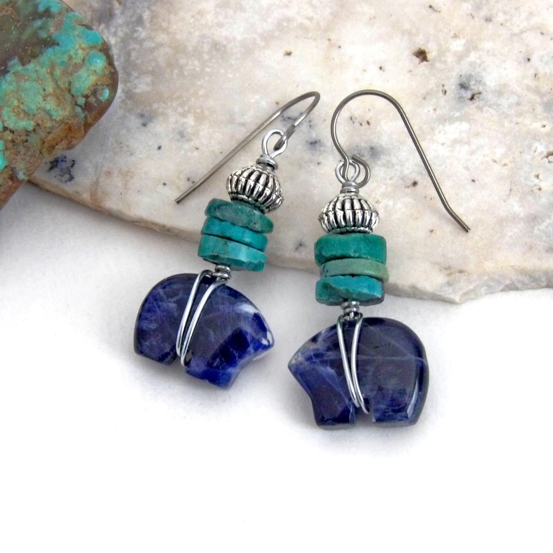 Small and cute, these zuni bear earrings feature natural blue sodalite gemstones carved into zuni bear shapes wrapped in steel wire and accented with turquoise heishi and silver tone pewter beads. They'll make a great gift for an animal / bear lover or anyone that loves southwestern style! These carved stone animals are believed by the Zuni people to hold the living spirit and power of the bear which represents healing, protection, introspection, and is the revered Guardian of the West.