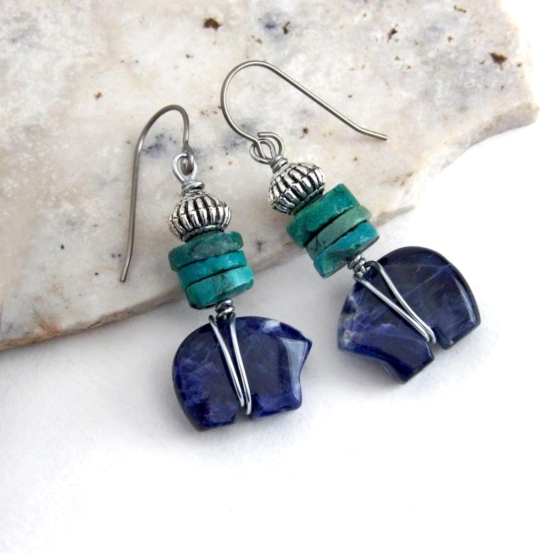 Small and cute, these zuni bear earrings feature natural blue sodalite gemstones carved into zuni bear shapes wrapped in steel wire and accented with turquoise heishi and silver tone pewter beads. They'll make a great gift for an animal / bear lover or anyone that loves southwestern style! These carved stone animals are believed by the Zuni people to hold the living spirit and power of the bear which represents healing, protection, introspection, and is the revered Guardian of the West.