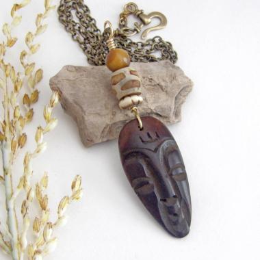 This handcrafted necklace features a carved wood African mask accented with a giraffe print etched agate, golden tiger's eye gemstones and an African carved bone bead. Unique and striking, it'll make a great gift for someone that loves one-of-a-kind ethnic inspired jewelry! It comes on an 18” antiqued brass chain with sturdy hook & eye closure.  Makes a great gift for a man or women that loves African art!