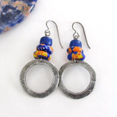 These handcrafted earrings feature silver pewter circle hoops with a hand stamped texture accented with colorful African glass beads and navy blue glass beads. They have an earthy, boho style and are lightweight and comfortable to wear.  MEASUREMENTS: Total length 2" from top of gray silver niobium (hypoallergenic) ear wires and 1” at widest point. The circles were created out of solid lead-free pewter; hand stamped and oxidized; and signed on the back with my initials
